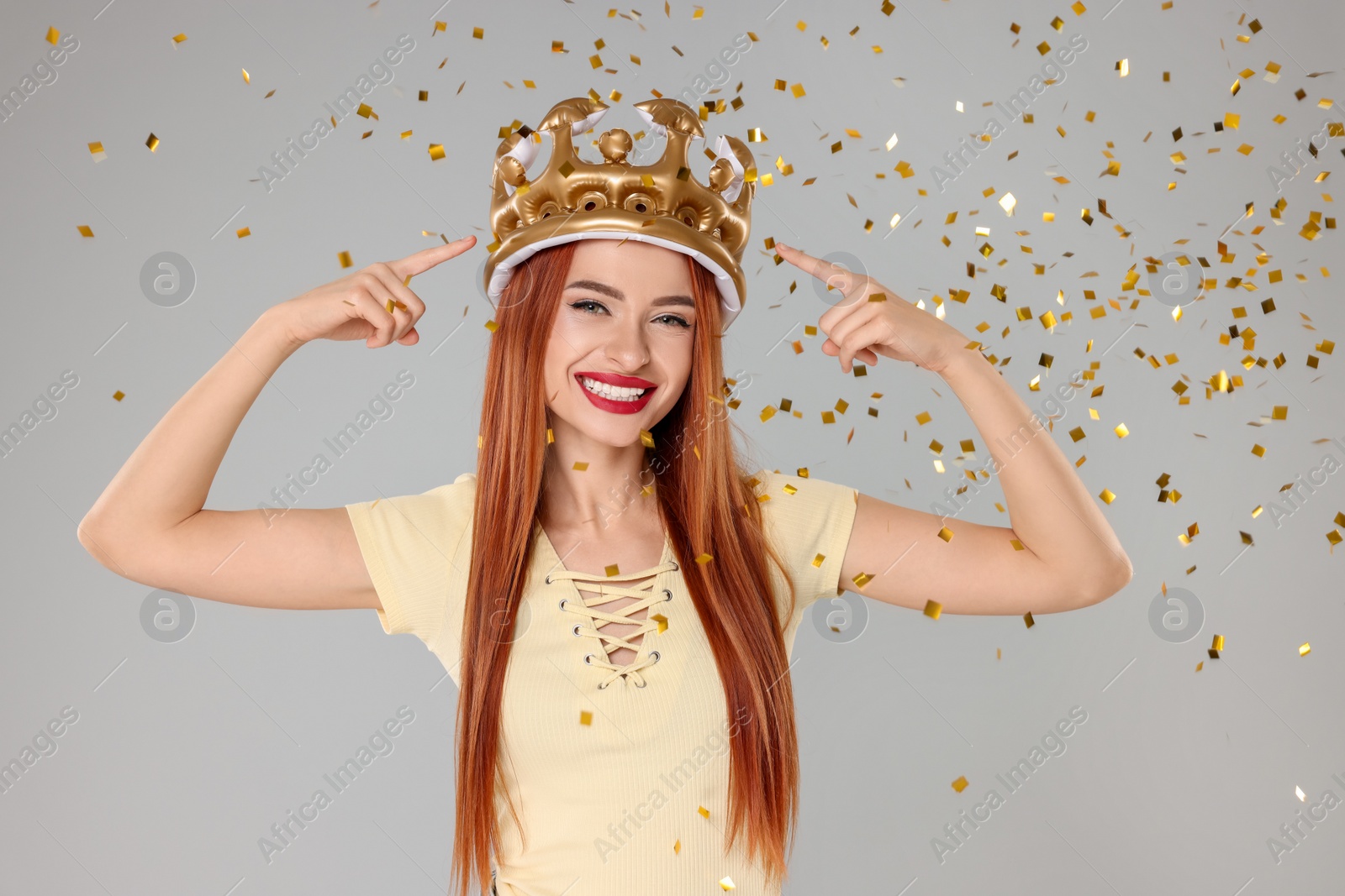 Photo of Beautiful young woman with inflatable crown on light grey background