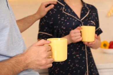 Photo of Couple in pajamas with mugs at home, closeup