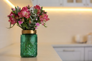 Photo of Vase with beautiful alstroemeria on countertop in kitchen, space for text. Interior design