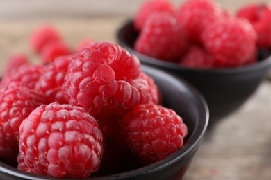 Tasty ripe raspberries in black bowl, closeup. Space for text