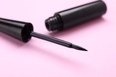 Photo of Black eyeliner on pink background, closeup. Makeup product