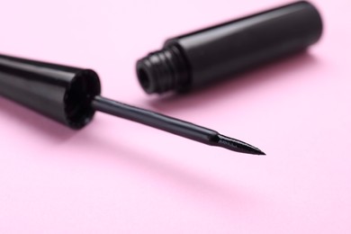 Black eyeliner on pink background, closeup. Makeup product