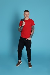 Photo of Young man with tattoos on light blue background