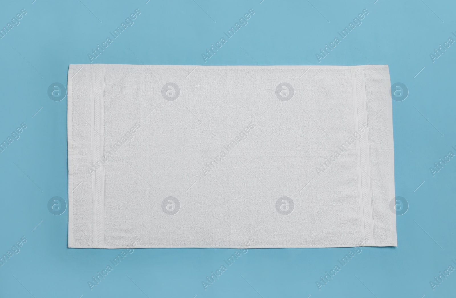 Photo of White beach towel on light blue background, top view