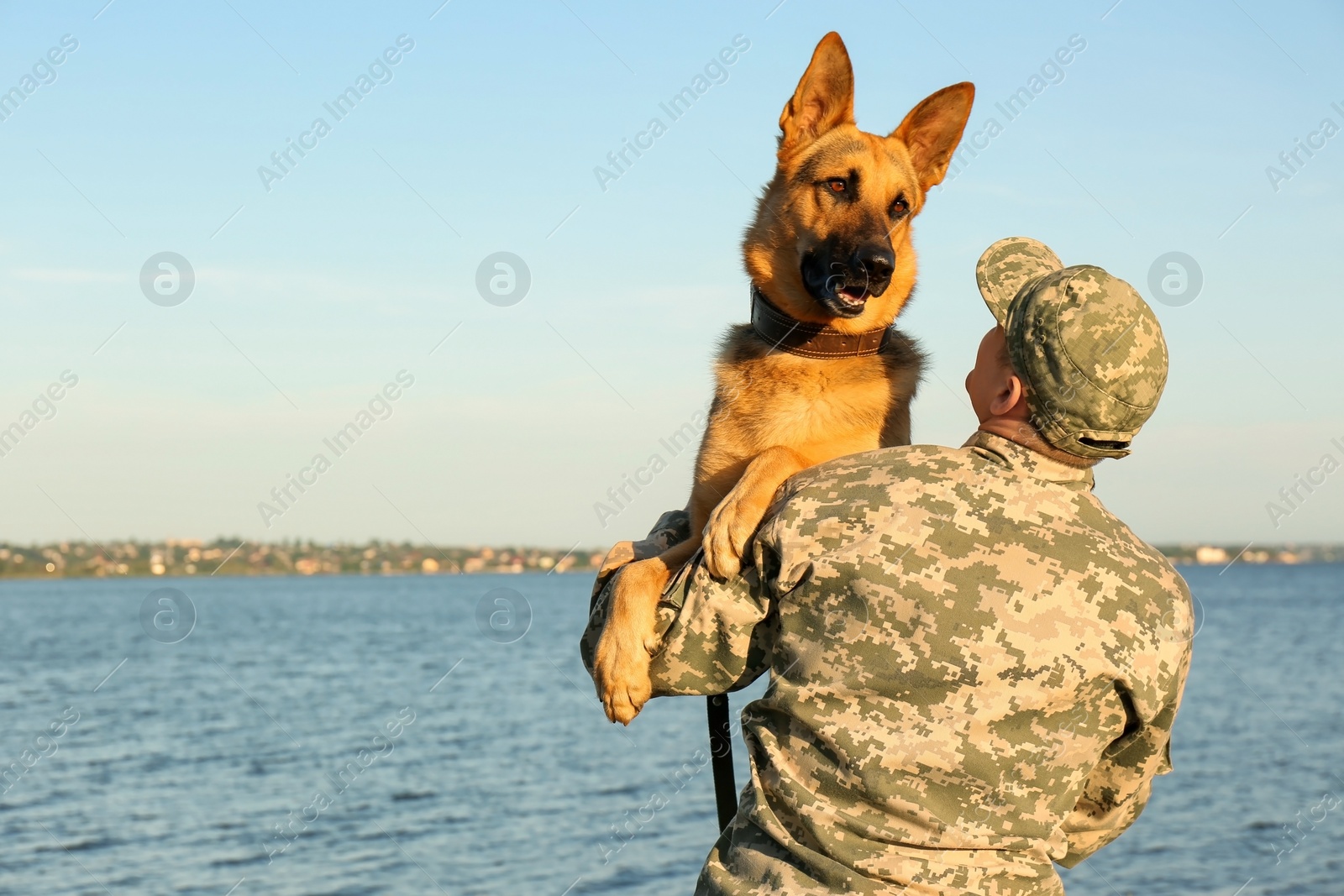 Photo of Man in military uniform with German shepherd dog outdoors