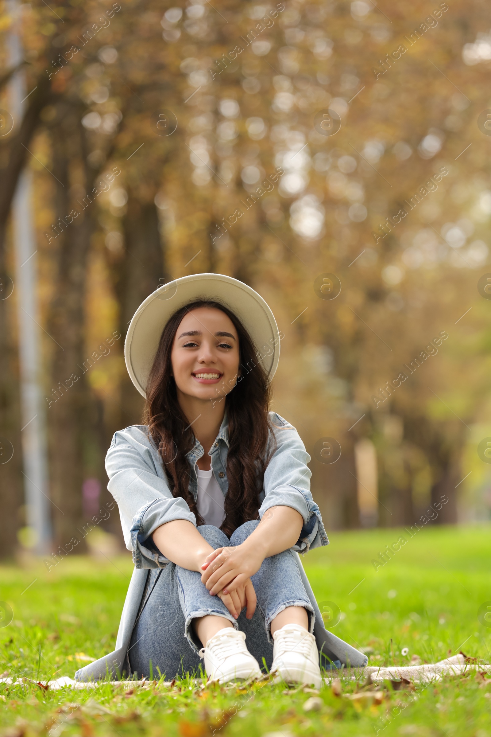 Photo of Young woman sitting on green grass in park