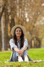 Young woman sitting on green grass in park