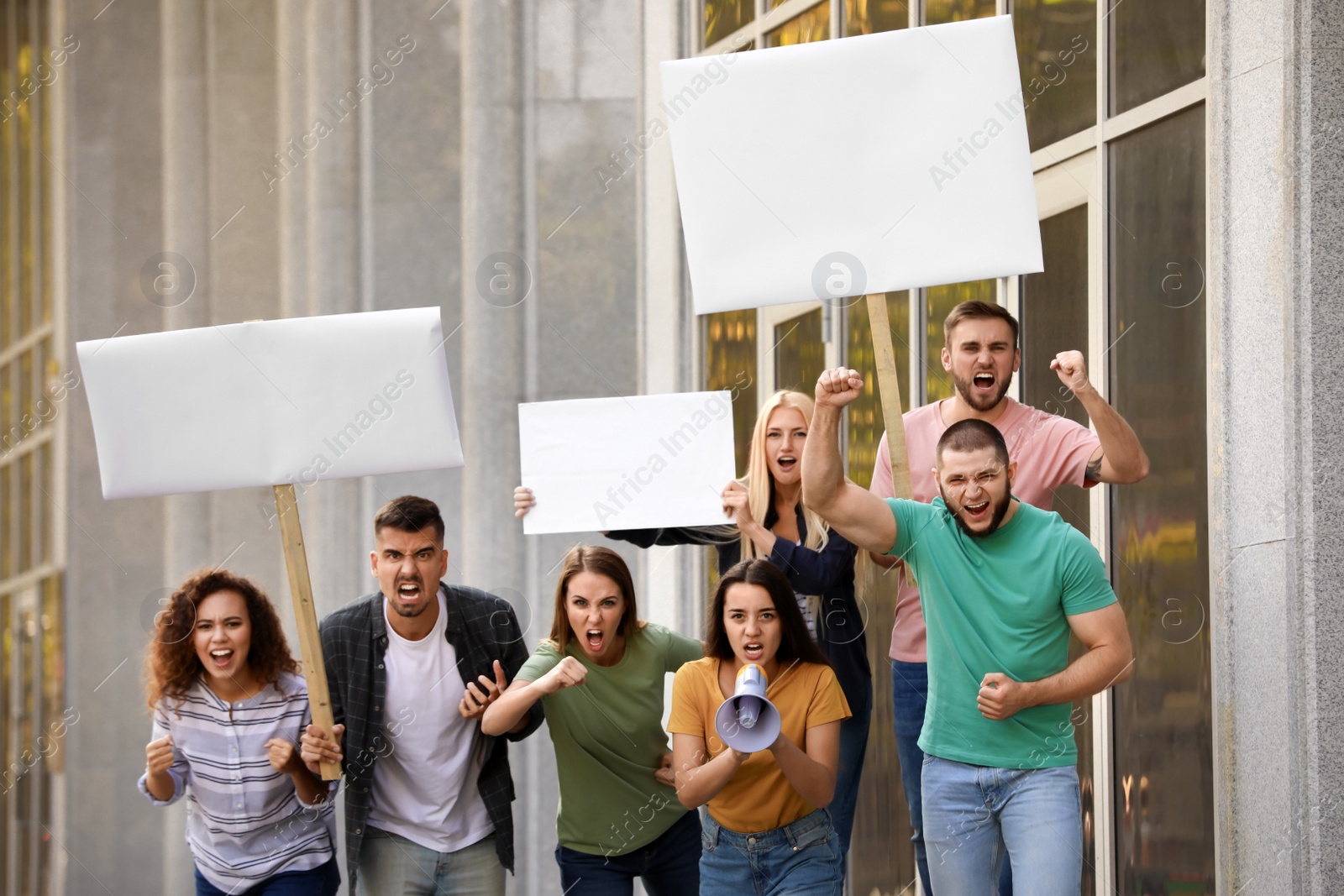 Photo of Angry young woman with megaphone leading protest outdoors