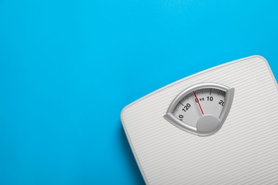 Photo of Bathroom scale on light blue background, top view. Space for text