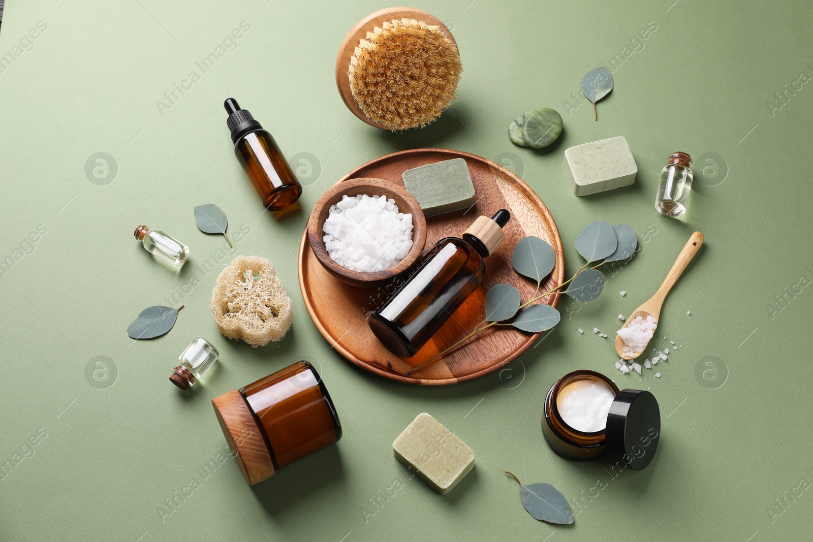 Photo of Composition with different spa products and eucalyptus branches on olive background, above view