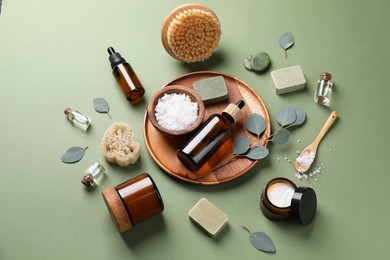 Composition with different spa products and eucalyptus branches on olive background, above view