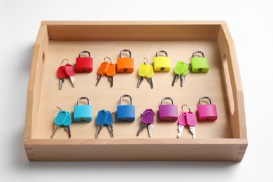 Photo of Set of colorful locks and matching keys in box isolated on white. Montessori toy
