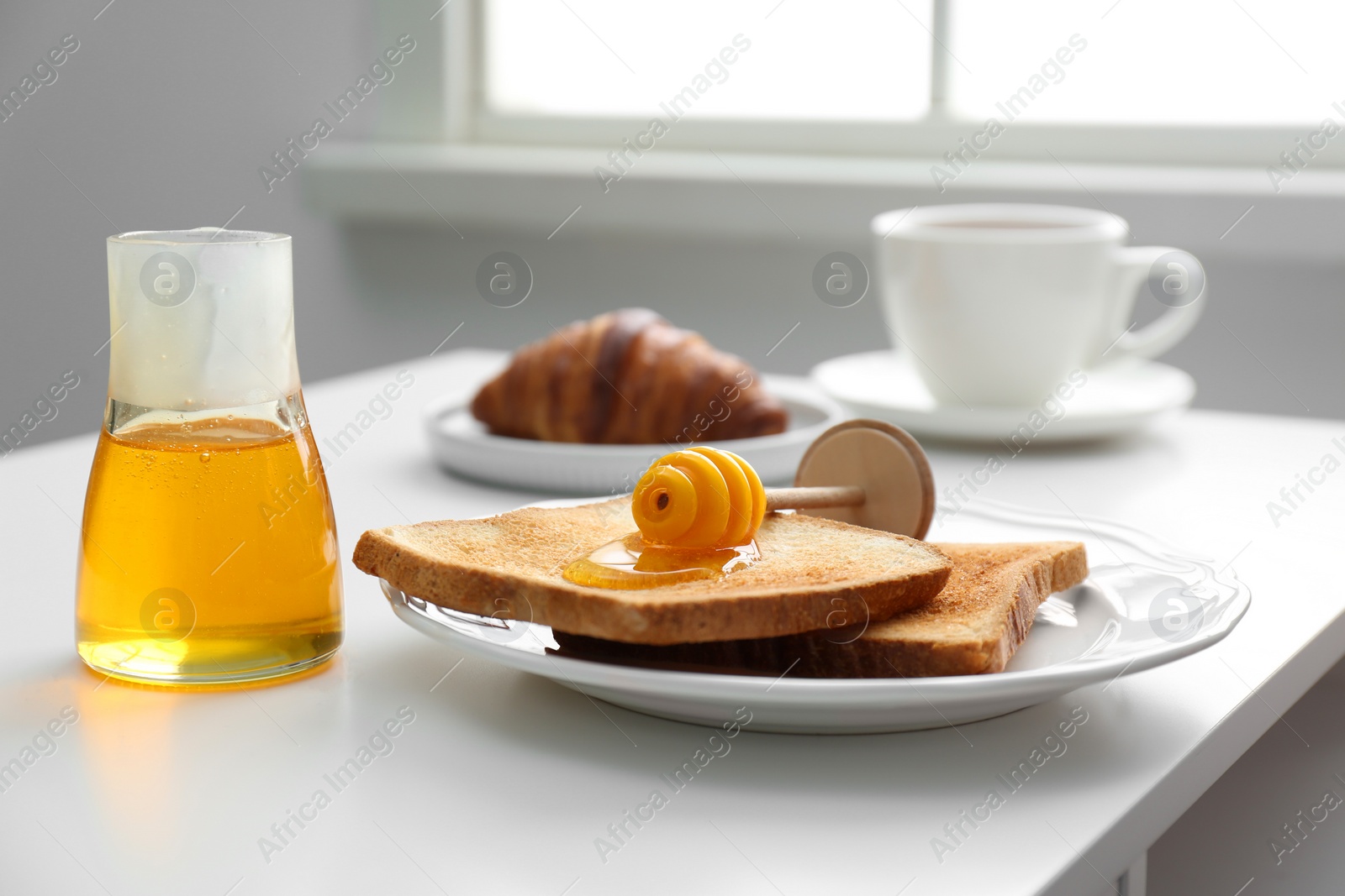 Photo of Delicious honey and toasts on white table