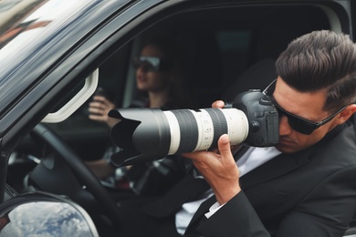 Photo of Private detectives with modern camera spying from car