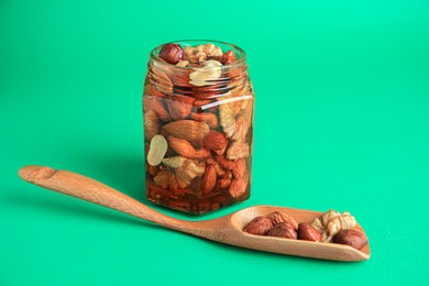 Different tasty nuts with honey on green background