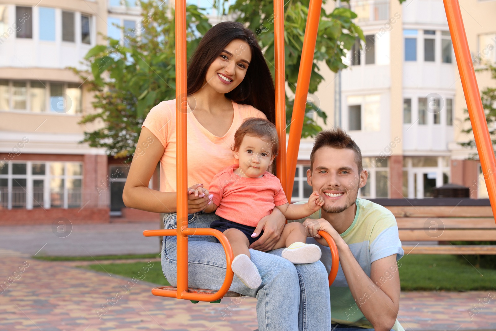 Photo of Happy family with adorable little baby at playground