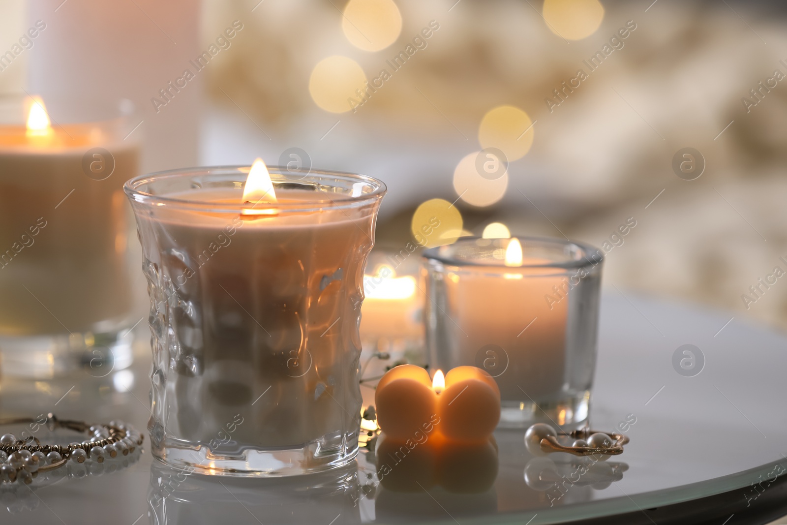 Photo of Burning candles and jewelry on table indoors