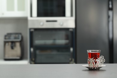 Photo of Glass of delicious tea in vintage holder on grey table. Space for text