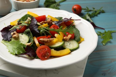 Photo of Tasty fresh vegetarian salad on light blue wooden table, closeup