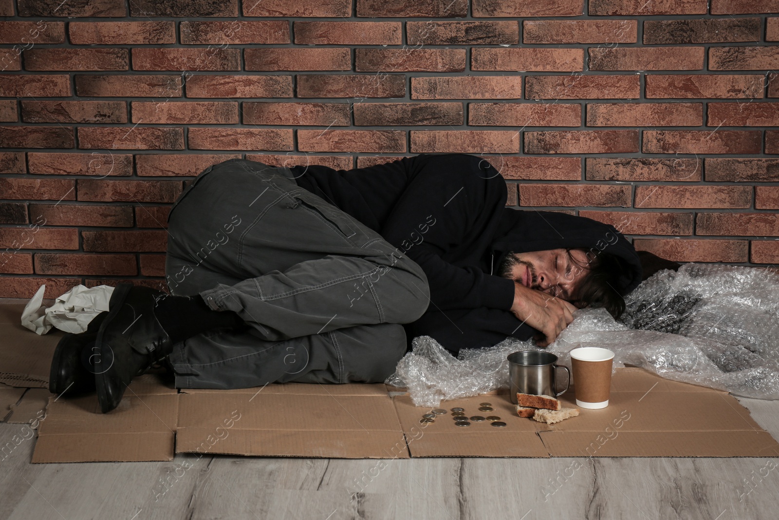 Photo of Poor man sleeping on floor near brick wall