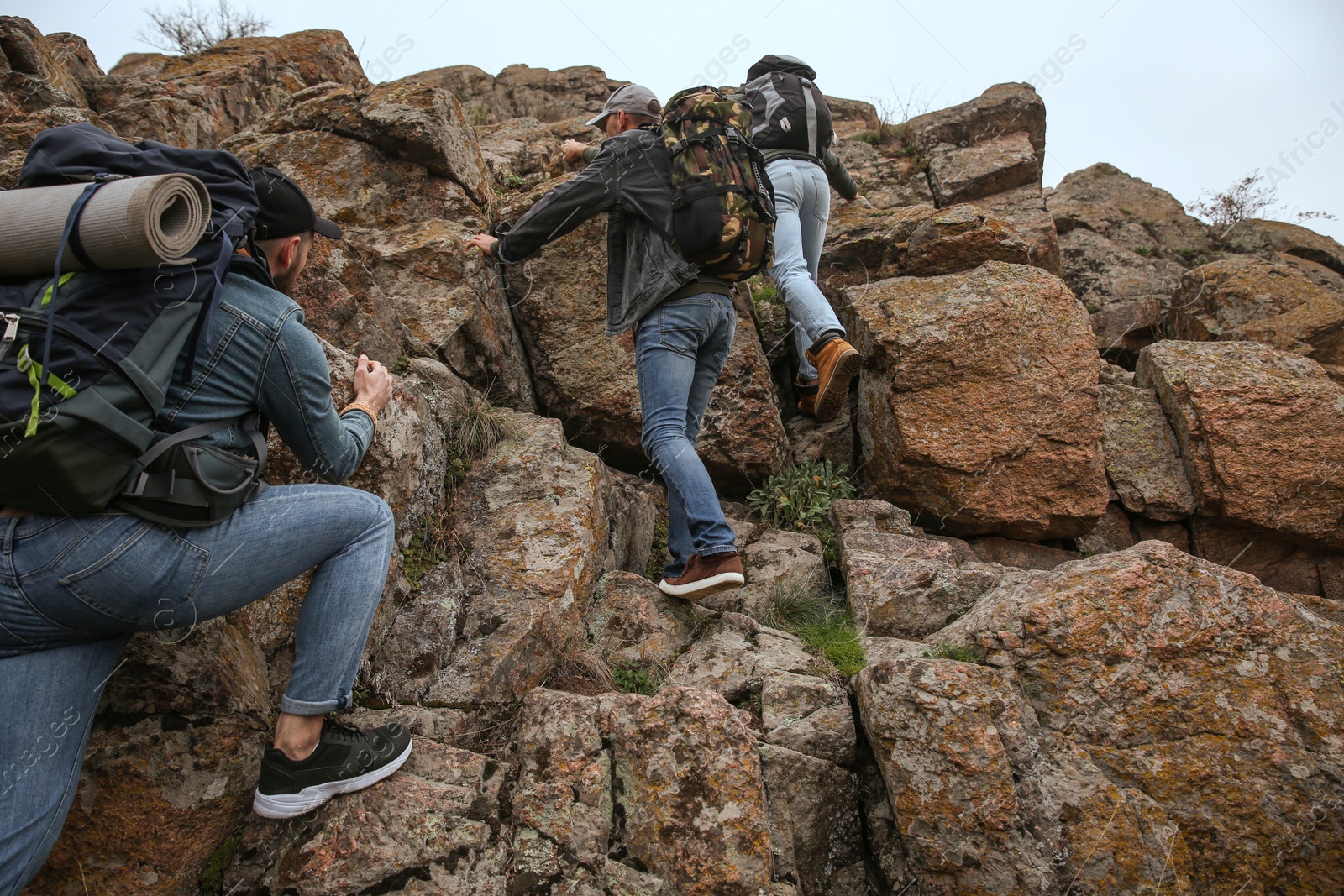 Photo of Group of hikers with backpacks climbing up mountains