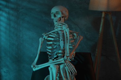 Waiting concept. Human skeleton sitting in armchair indoors