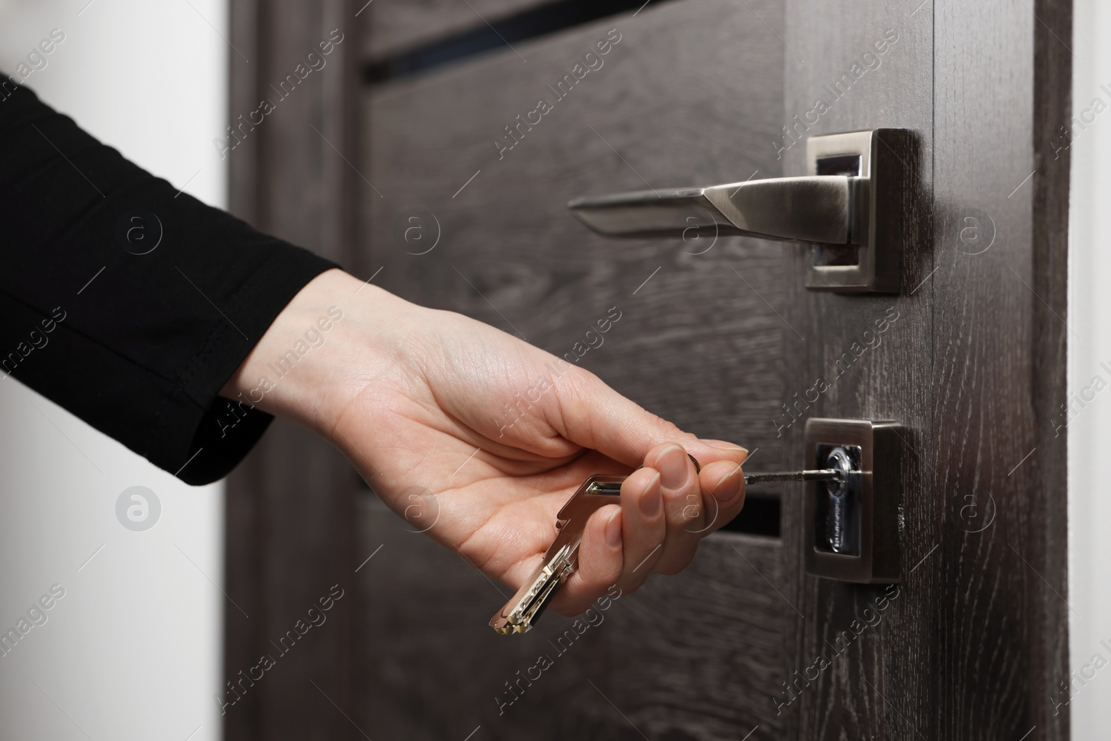 Photo of Woman unlocking door with key, closeup view
