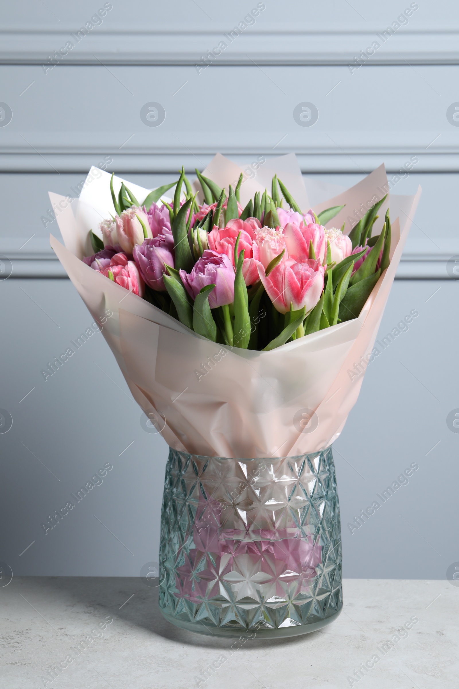 Photo of Vase with bouquet of beautiful tulips on grey table