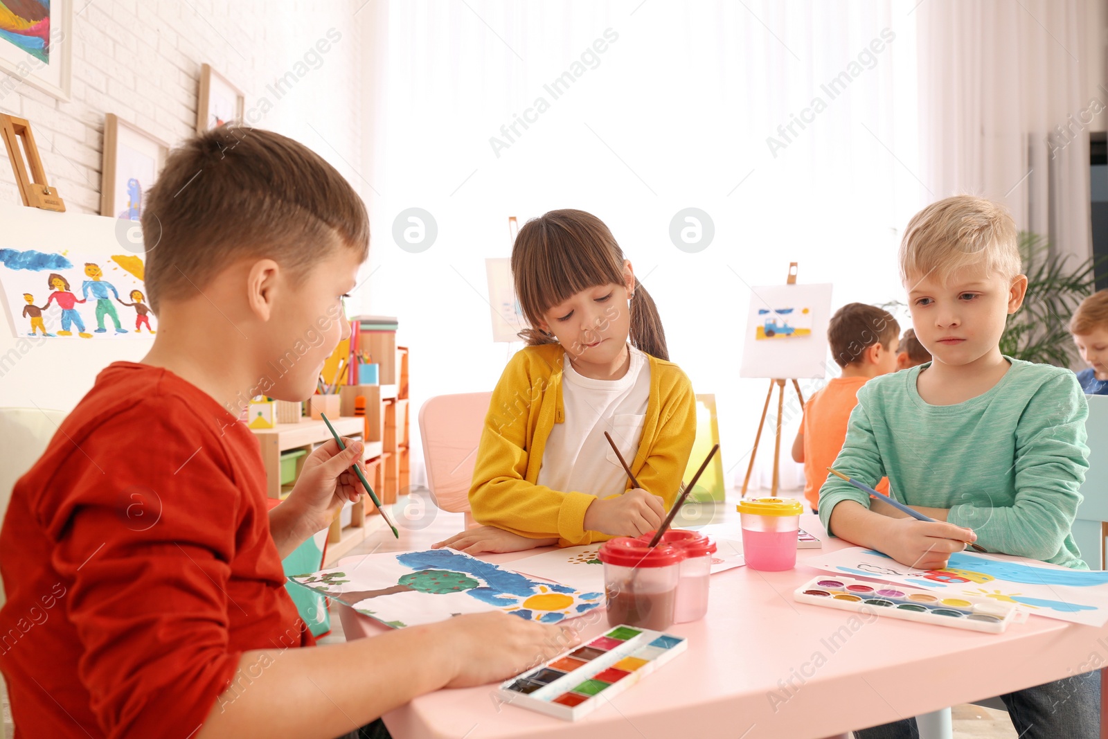 Photo of Cute little children painting at table in room