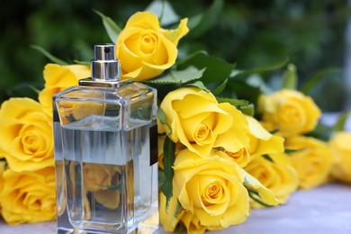 Photo of Perfume and beautiful bouquet of yellow roses on light table outdoors, closeup. Space for text