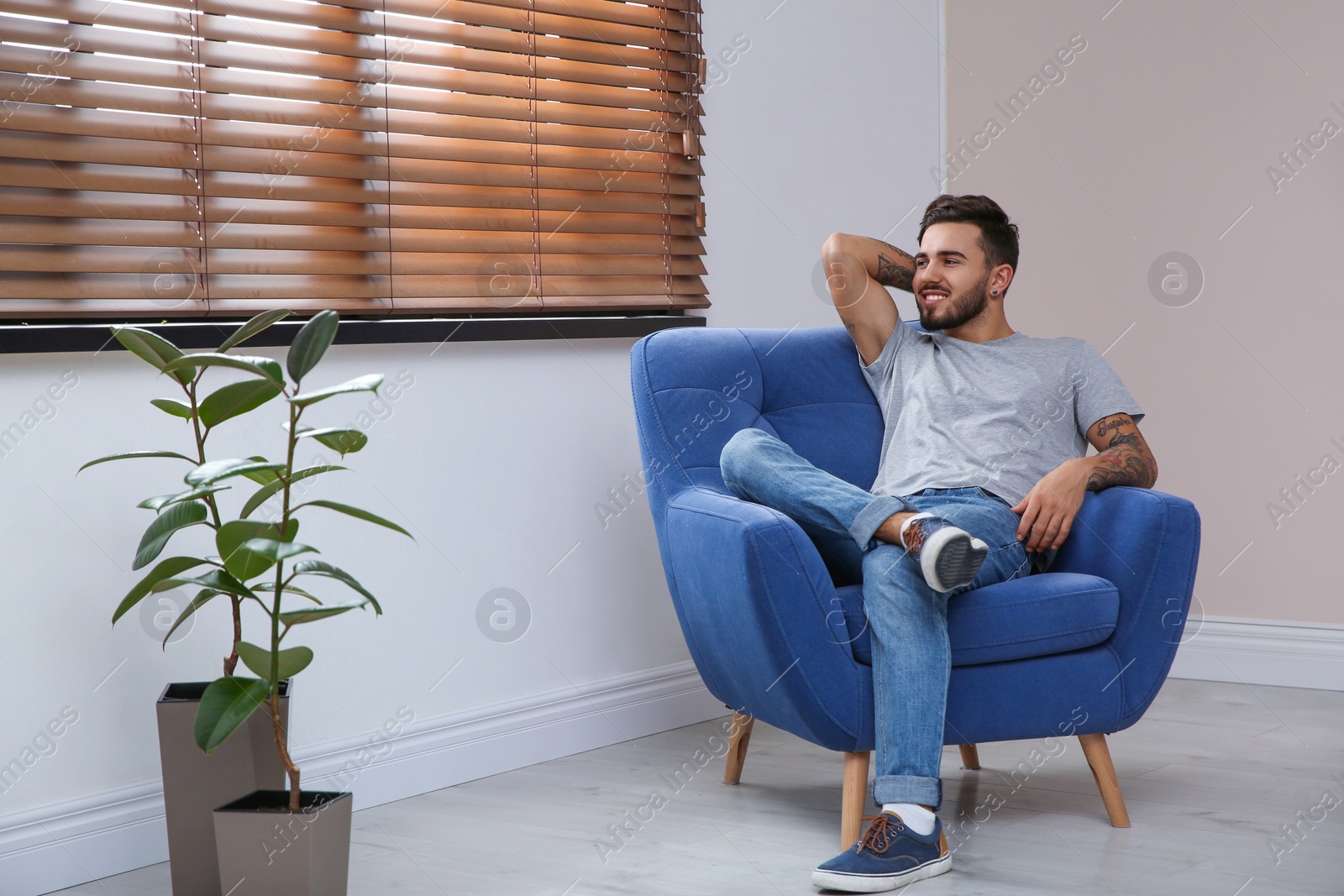 Photo of Young man relaxing in armchair near window