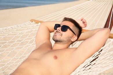 Photo of Young man relaxing in hammock on beach