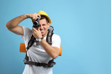 Photo of Male tourist with travel backpack taking picture on turquoise background, space for text
