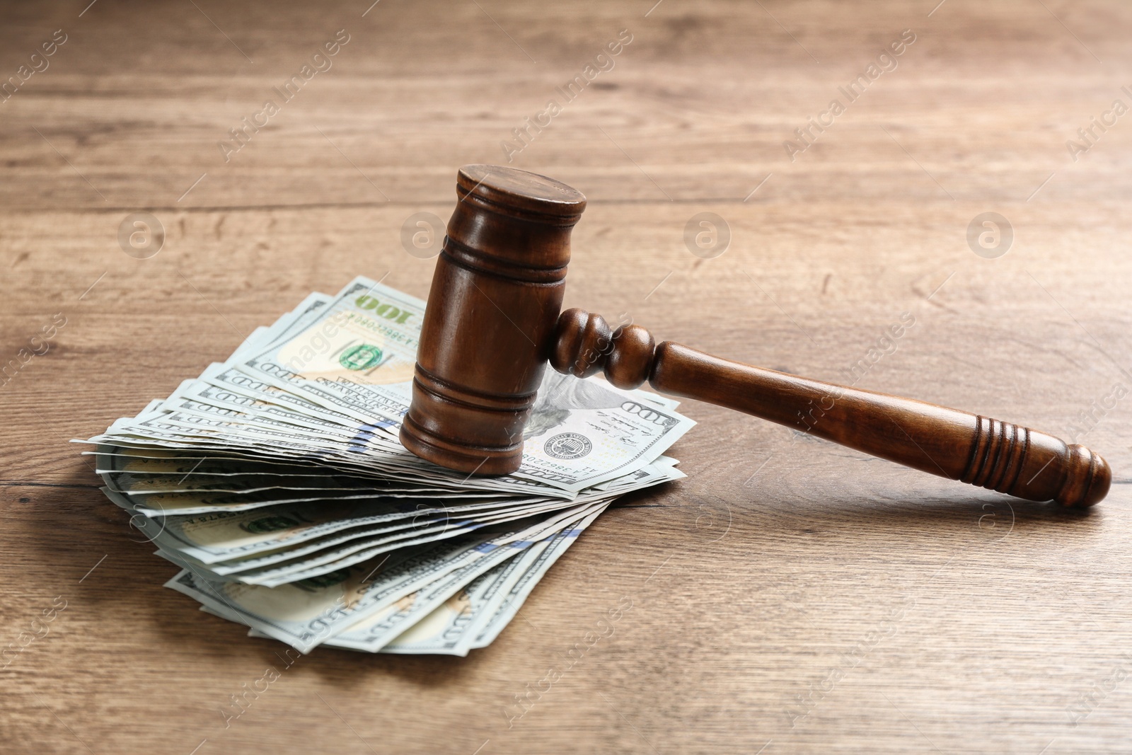 Photo of Dollar bills and gavel on wooden table. Bribe concept