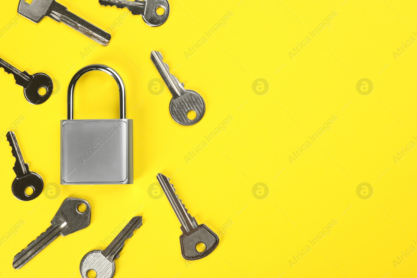 Photo of Modern padlock with keys on yellow background, flat lay. Space for text