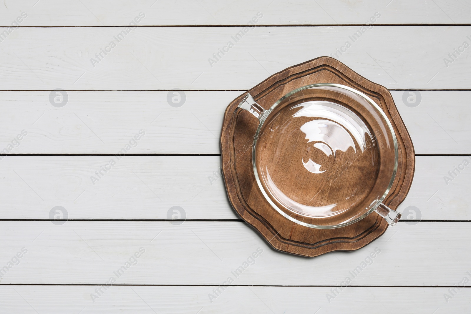Photo of Empty glass pot and board on white wooden table, top view. Space for text