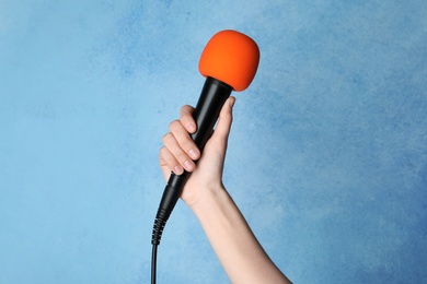 Photo of Woman holding microphone on color background, closeup