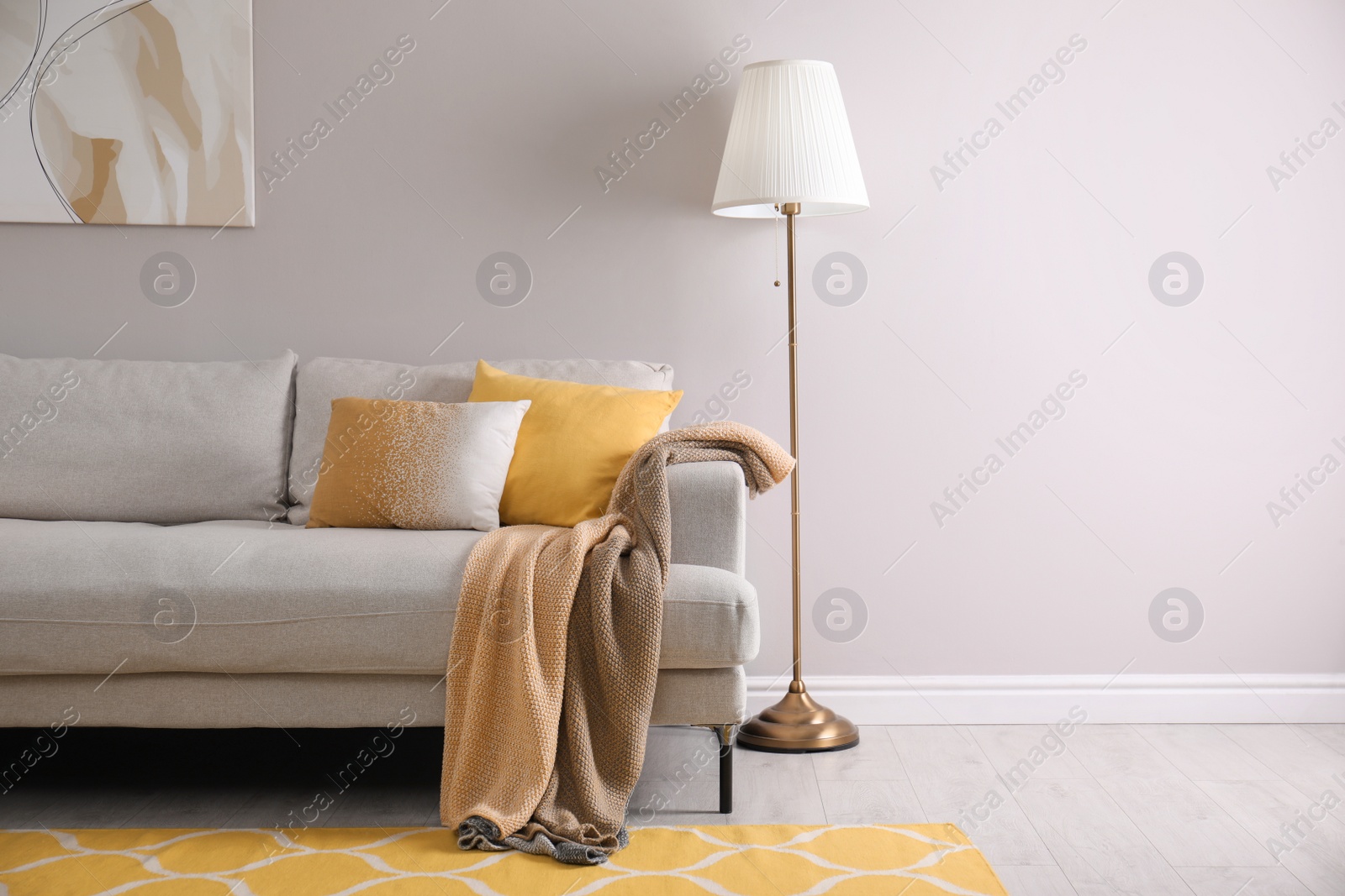 Photo of Comfortable sofa with cushions and plaid in stylish living room, space for text. Interior design