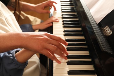 Photo of Young woman with child playing piano, closeup. Music lesson