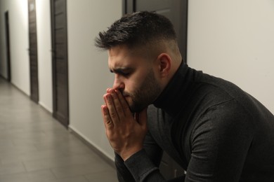 Photo of Sad young man in hall. Space for text