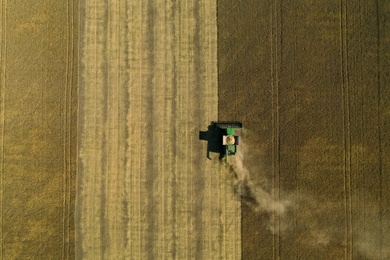 Beautiful aerial view of modern combine harvester working in field on sunny day. Agriculture industry