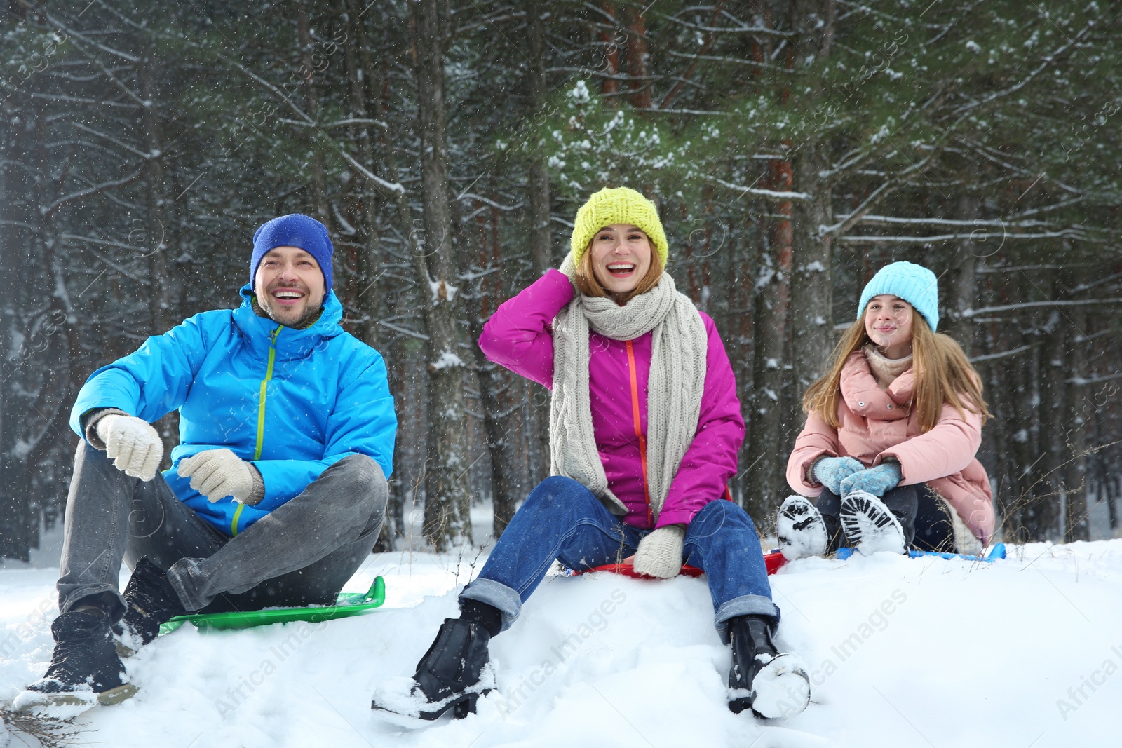 Photo of Happy family sledding in forest on snow day