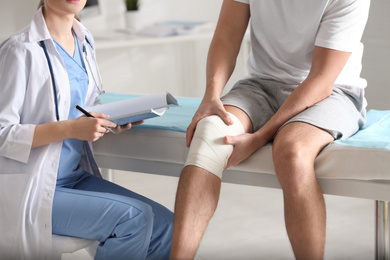 Photo of Female orthopedist examining patient with injured knee in clinic, closeup
