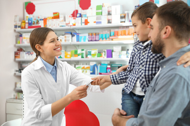 Professional pharmacist giving pills to customer in modern drugstore