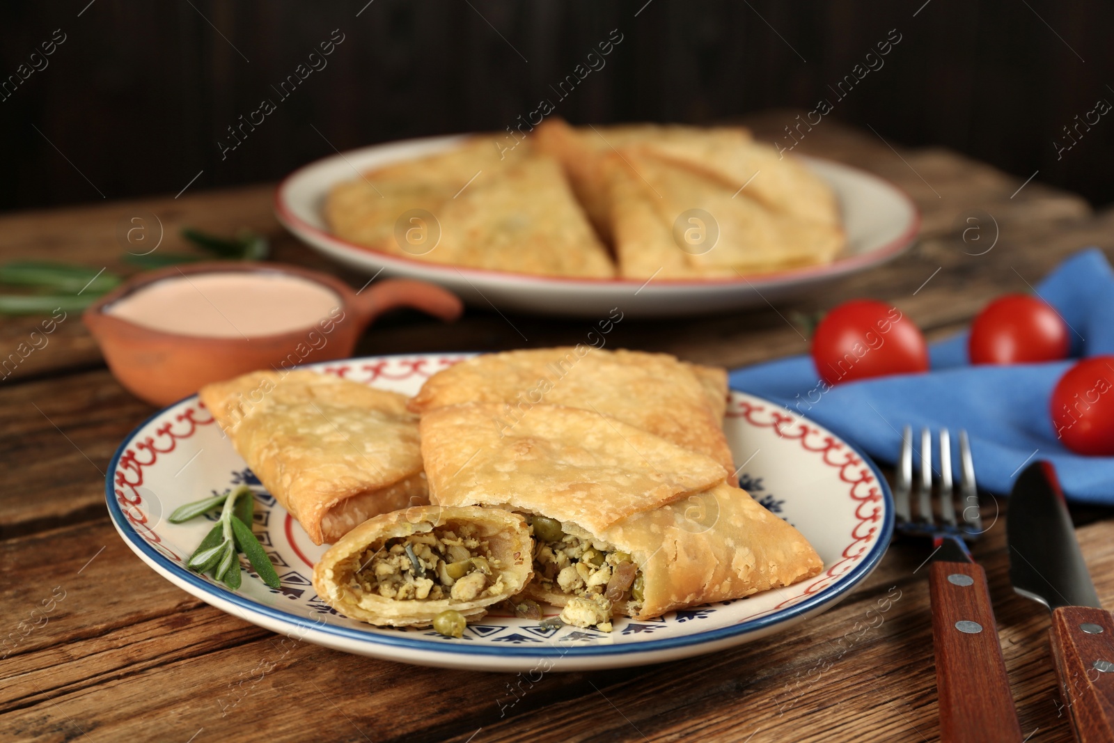 Photo of Delicious samosas with sauce served on wooden table, closeup