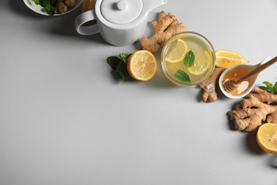 Delicious ginger tea and ingredients on light grey background, flat lay. Space for text