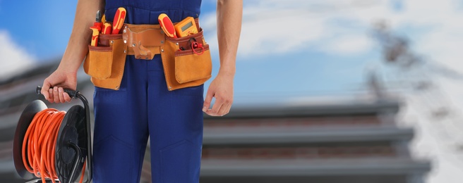 Closeup view of electrician with tools at site, space for text. Banner design