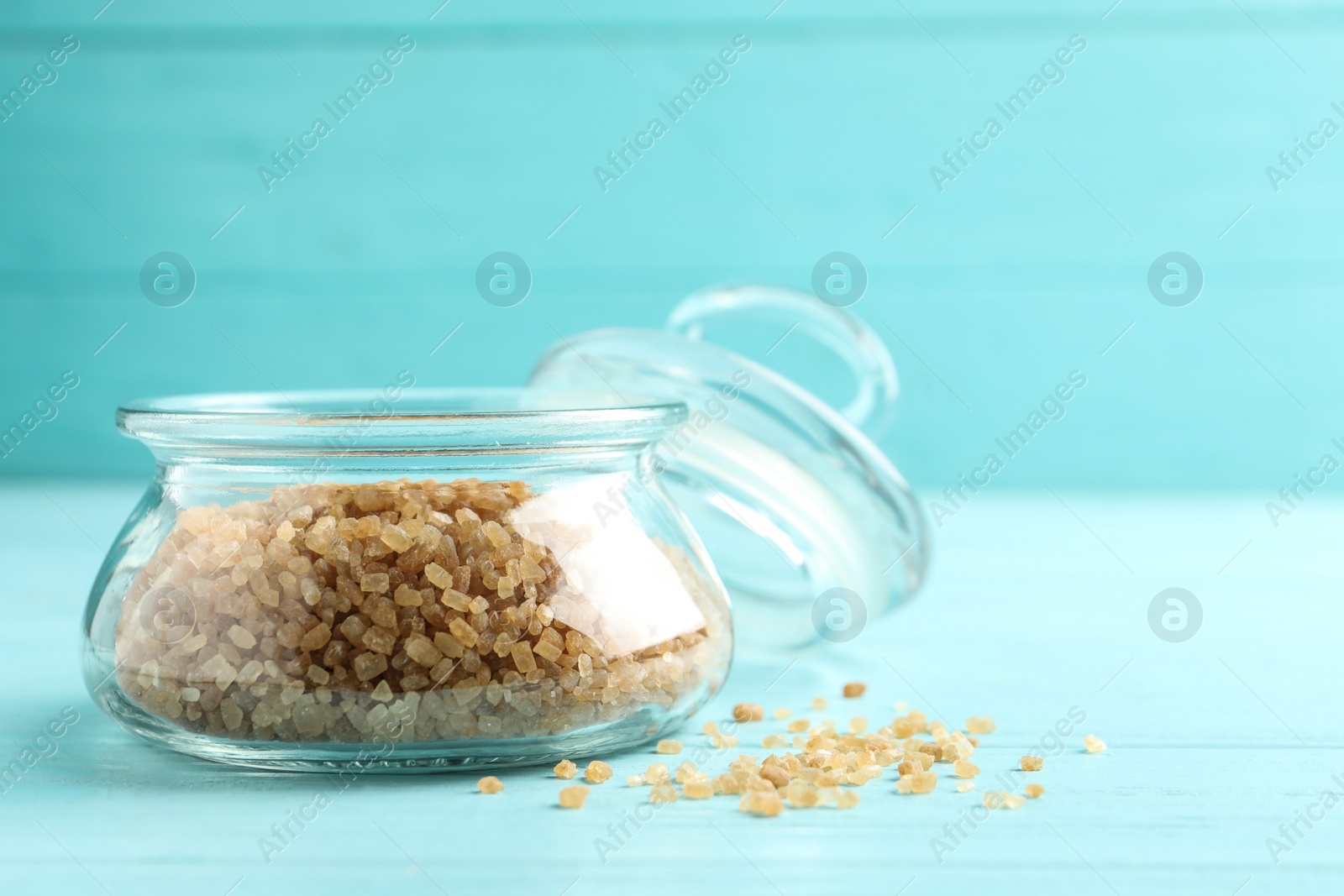 Photo of Glass bowl with brown sugar on light blue wooden table. Space for text