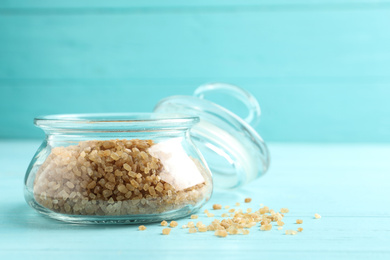 Glass bowl with brown sugar on light blue wooden table. Space for text