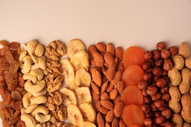 Mix of delicious dried nuts and fruits on beige background, flat lay